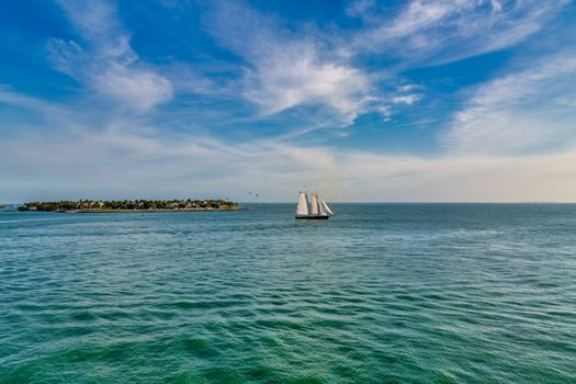 Schooner under sails sailing across a bay under beautiful skies