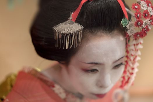 Japanese Maiko or geisha in red kimono coifed hair brooch with patterns of red and white plum blossoms