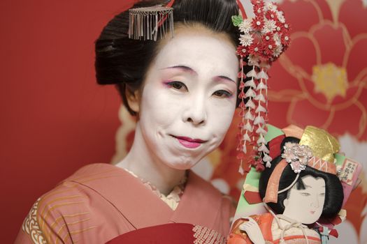 Geisha holding an hagoita doll.
