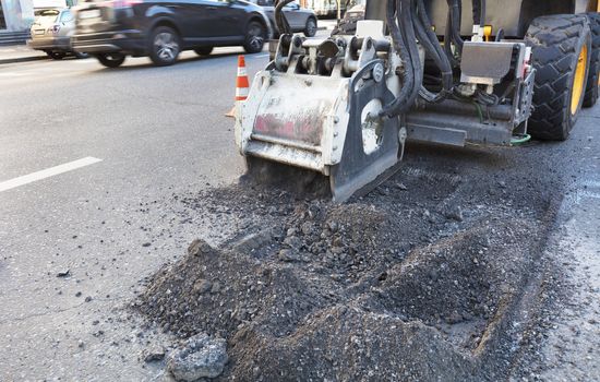 On a city road the tractor with a nozzle for repair of a surface on asphalt does the work