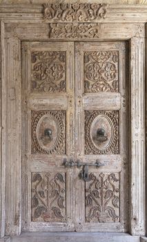 Ancient antique wooden doors of an old hut with a wrought iron crossbar and metal handles