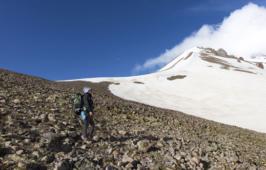 Woman tourist with a backpack goes to trekking on a snowy mountain