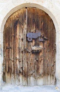 Very old weathered arch antique wooden doors with a metal wrought iron lock