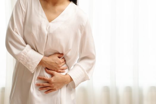 Young woman suffering from abdominal pain feeling stomachache, symptom of pms on white background