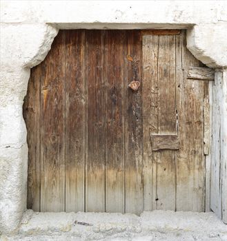 Very old weathered trapezoidal antique wooden doors with a wooden lock