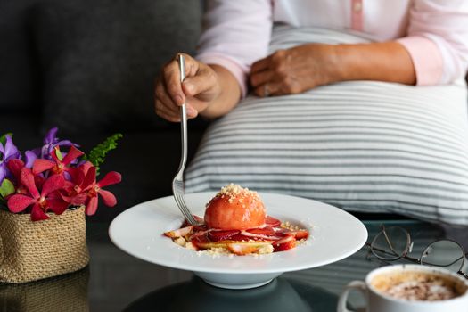 old woman hold folk with freshly homemade Pancakes Strawberry Crumble on white dessert plate