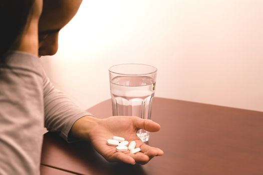 underexpose of the headache women hand holding the medicine with a glass of water, medicine recovery concept