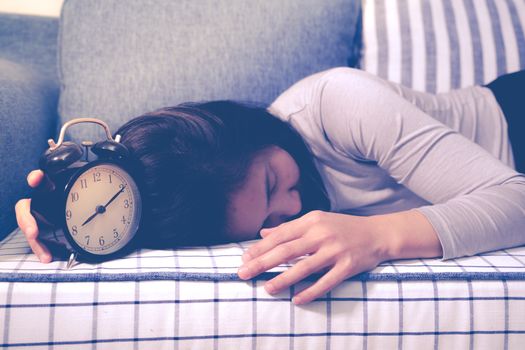 Lazy women is laying down on the sofa after the clock alarm, late wakeup lifestyle concept