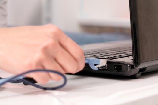 women hand is plugging in the lan cable to laptop port
