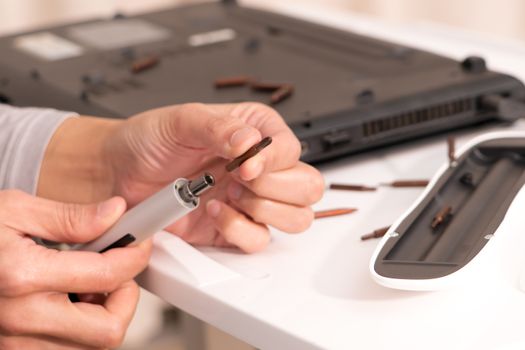 focus on women hand hold the screw driver to repair the laptop, repair and maintenance