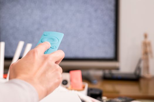 a women hand hold the remote control of the TV box in the living room, the blank screen TV