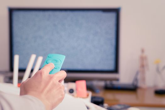 a women hand hold the remote control of the TV box in the living room, the blank screen TV