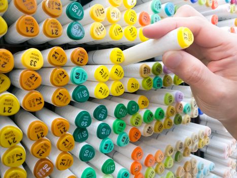 focus on women hand select the color pen on the shelf at stationery shop