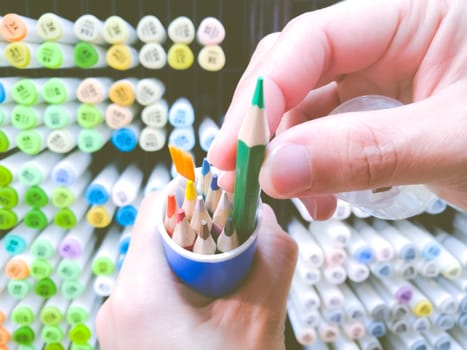 focus on women hand select the color pen on the box with color pen shelf background