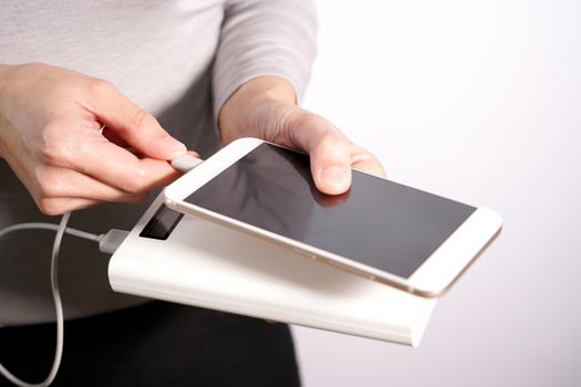 the women hand hold the phone and charger, powerbank and smart phone is connecting, energy