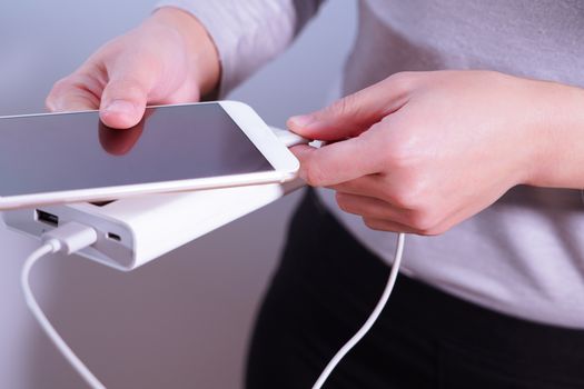 the women hand hold the phone and charger, powerbank and smart phone is connecting, energy