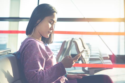 young women texting on mobile phone waiting for flying at airport window