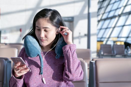 women texting on mobile phone waiting for flying at airport window