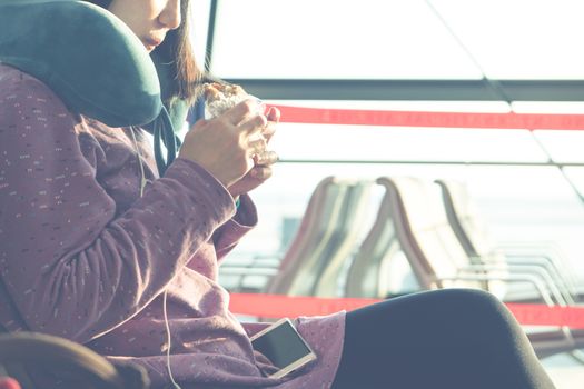 young women eating snack while waiting for flying at airport window