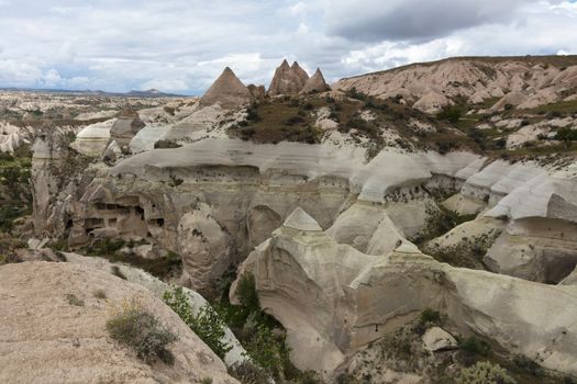 Red and white sandstone cliffs, ancient caves in a mountain landscape between valleys in Cappadocia, central Turkey