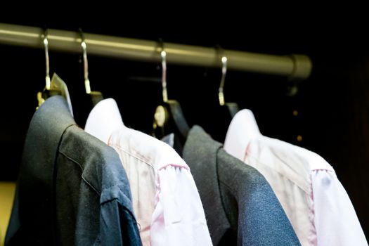 row of men and women shirts on the hanger, hanging in the wardrobe