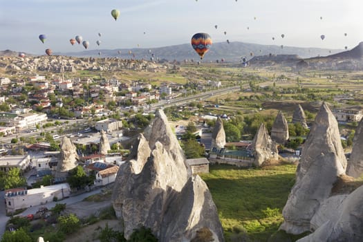 View of dozens of balloons flying over the valleys of Cappadocia at dawn in central Turkey.