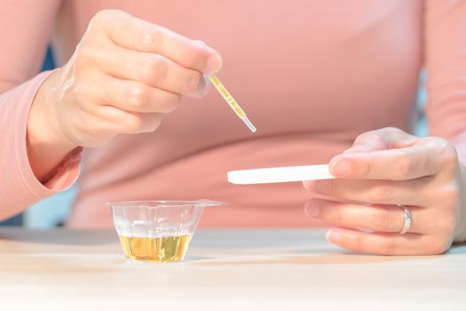 focus on the hand hold the pregnancy test pad while drop the urine on test pad