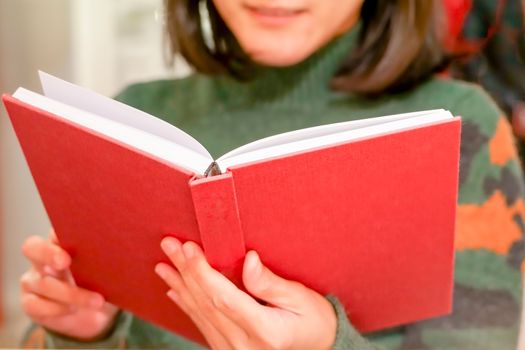 the open red book is holding/reading on women hand at home