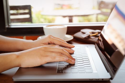 woman hands typing on laptop keyboard. Woman working at office with coffee