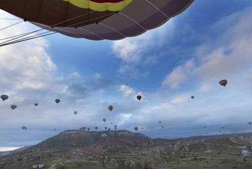 View of dozens of balloons flying over the valleys of Cappadocia at dawn in central Turkey.