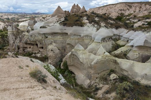 Red and white sandstone cliffs, ancient caves in a mountain landscape between valleys in Cappadocia, central Turkey