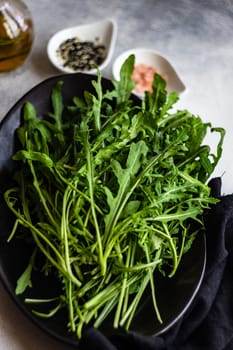 Healthy food concept with fresh organic arugula herb leaves on stone background with copy space