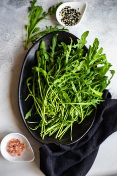 Healthy food concept with fresh organic arugula herb leaves on stone background with copy space