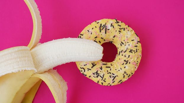 Sweet donut and banana on pink color background. Sex and Erotic concept