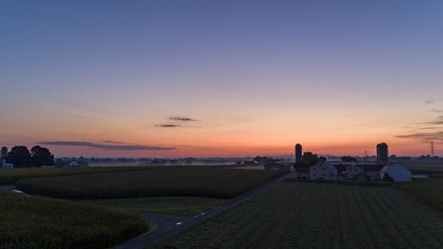 An Aerial View of a Sunrise Over an Amish Farm with Blues and Reds on a Clear Summer Morning
