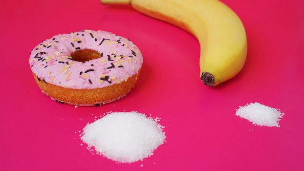 Choice donut against banana - sugar and calories in foods. Starting healthy eating or junk food. Pink background