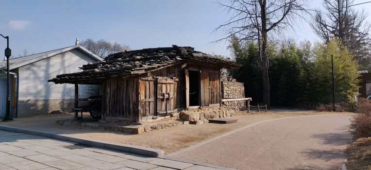 An abandoned old hut made out of wood with a horse cart in the back with an empty road