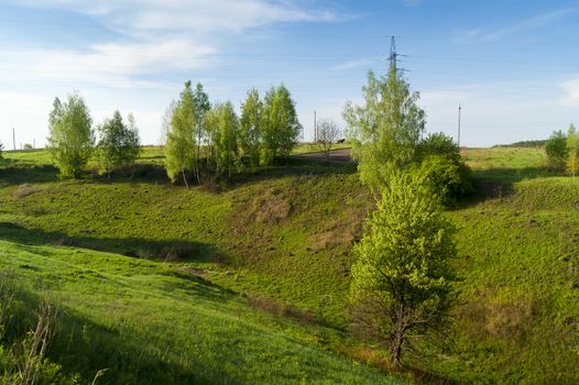 Green ravine, trees and blue sky with clouds