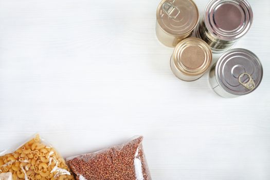 humanitarian assistance for poor and large families. Donation during crisis, pandemic or quarantine. Tin cans, canned food, stew, buckwheat, rice and pasta in transparent bags on white background.