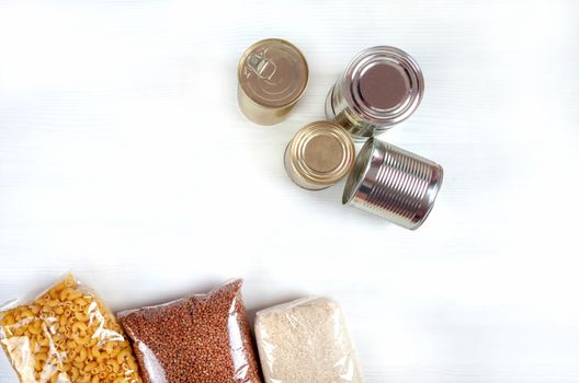 humanitarian assistance for poor and large families. Donation during crisis, pandemic or quarantine. Tin cans, canned food, stew, buckwheat, rice and pasta in transparent bags on white background.