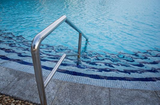 blue swimming pool with teak wood flooring stripes summer vacation