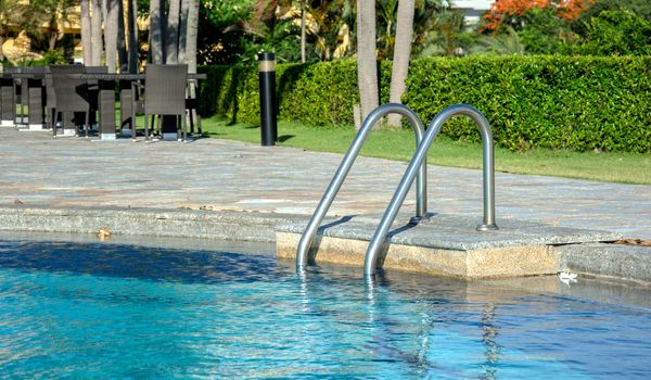 Grab bars ladder in the blue swimming pool
