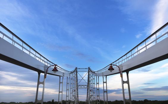 Evening blue sky, the setting sun is being trampled by the rays in the clouds. Symmetrical arches of the bridge are directed upwards.