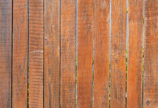 The aged old gray wooden fence is painted with orange paint, close-up