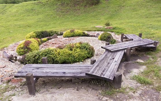 An old originalwooden bench, green bushes in a Japanese rock garden