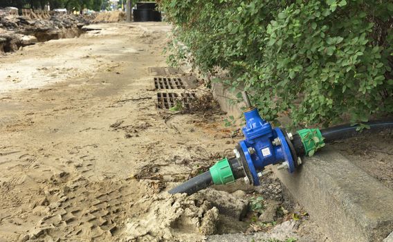 Water resistant water gate valves near the grilles of city stormworks near the excavated trench on the roadway of the street