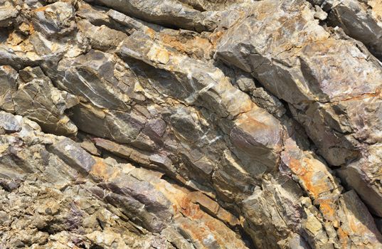 Texture of an old granite ridge. Abstract background of old stone, granite close-up in hard sunlight.