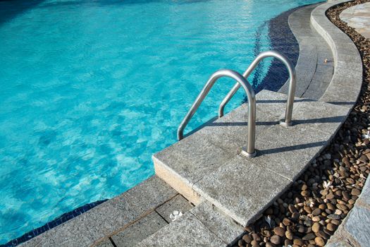 Grab bars ladder in the blue swimming pool