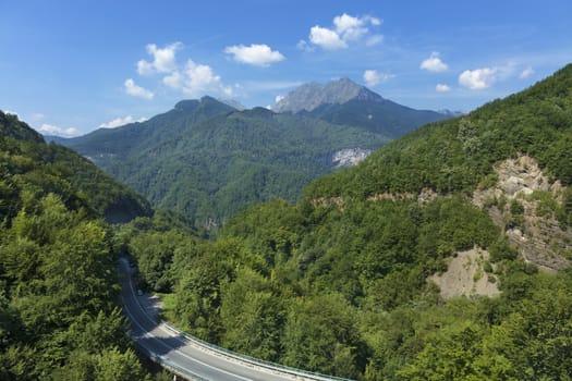 Aerial view of the greenery of the mountain massifs of Montenegro and the road, serpentine winding among the mountains.