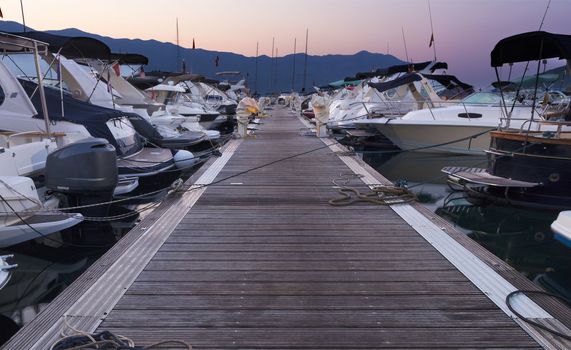 Morning at the sea pier, trail with many moored luxury and expensive yachts in the port of Budva, Montenegro.